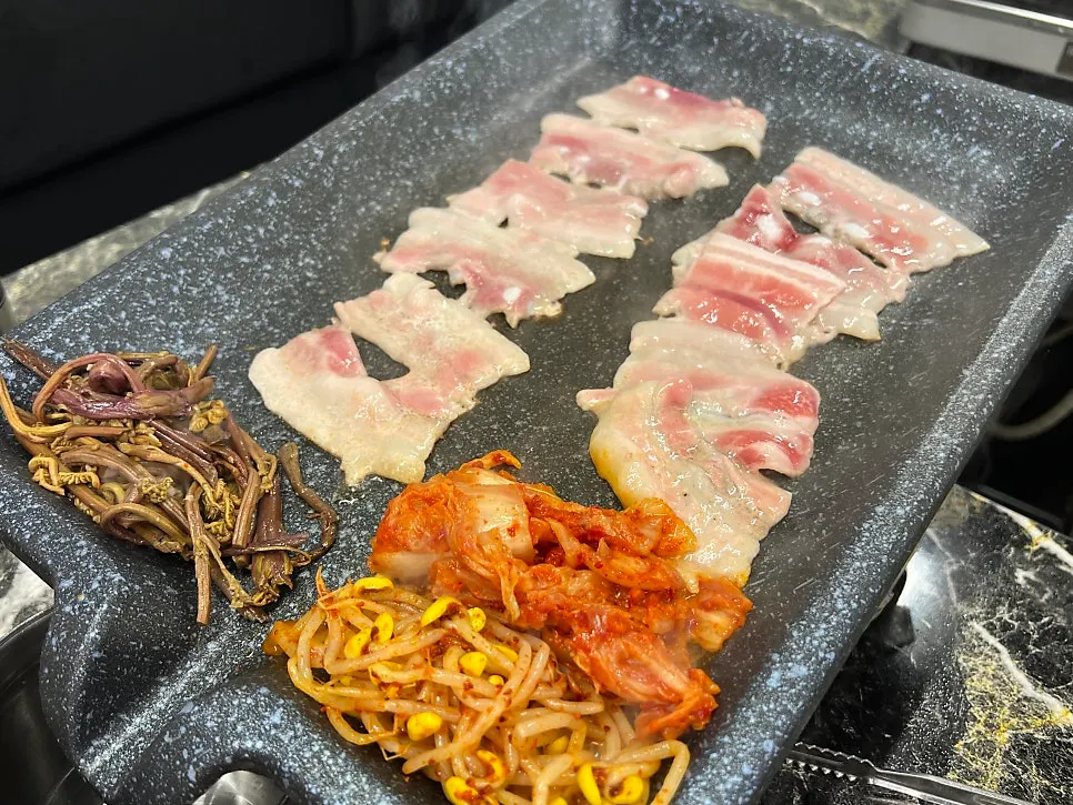 불판에 나물과 김치를 함께 올려 굽는 냉삼