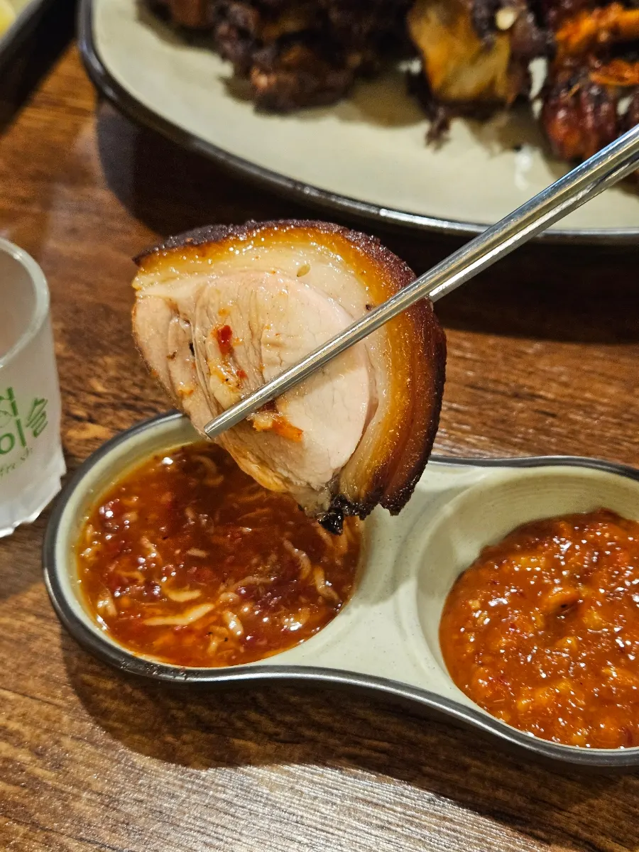 A piece of fried jokbal dipped in salted shrimp