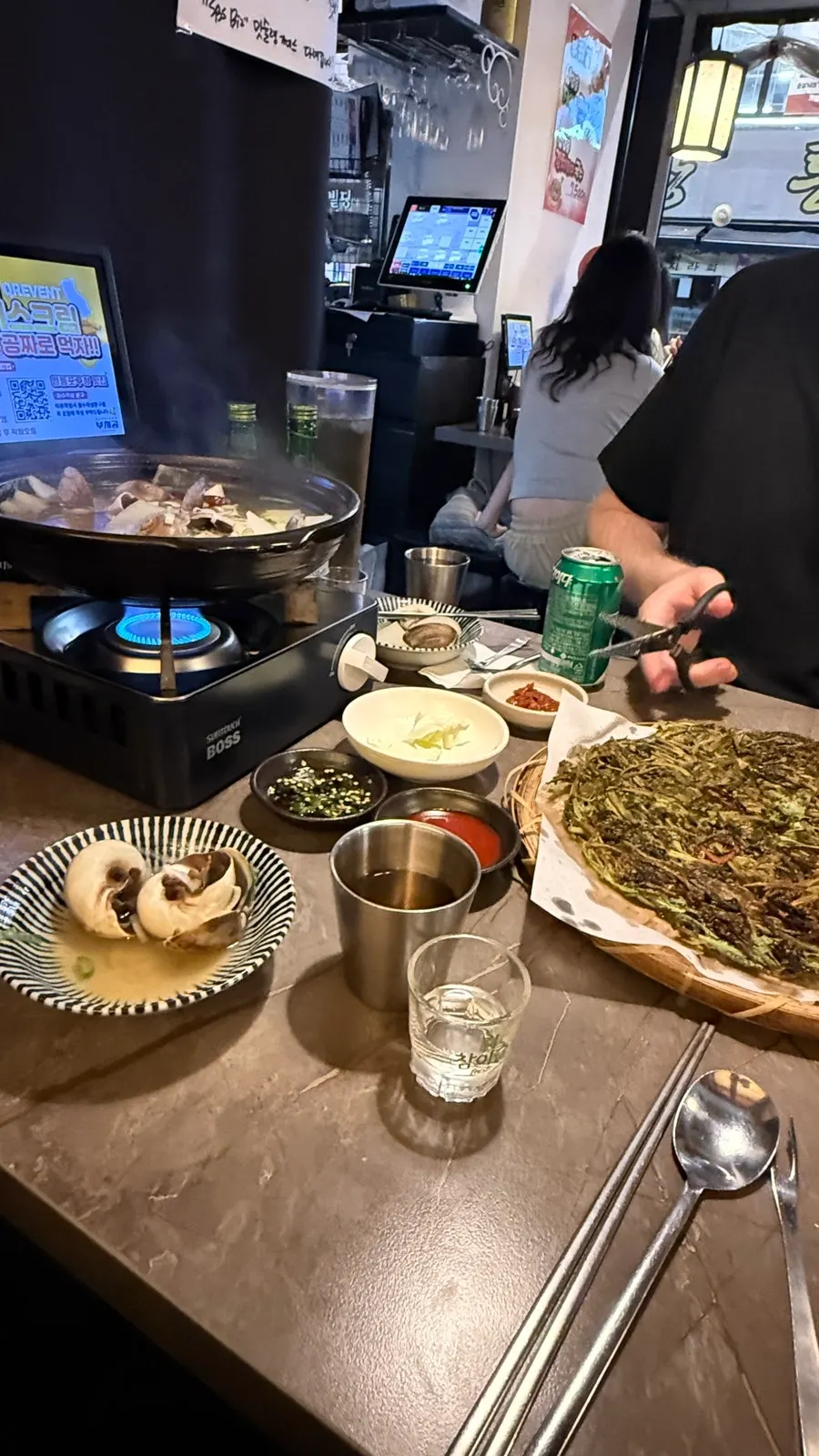 Table with whelk stew, minari pancake, and makgeolli for a drinking session