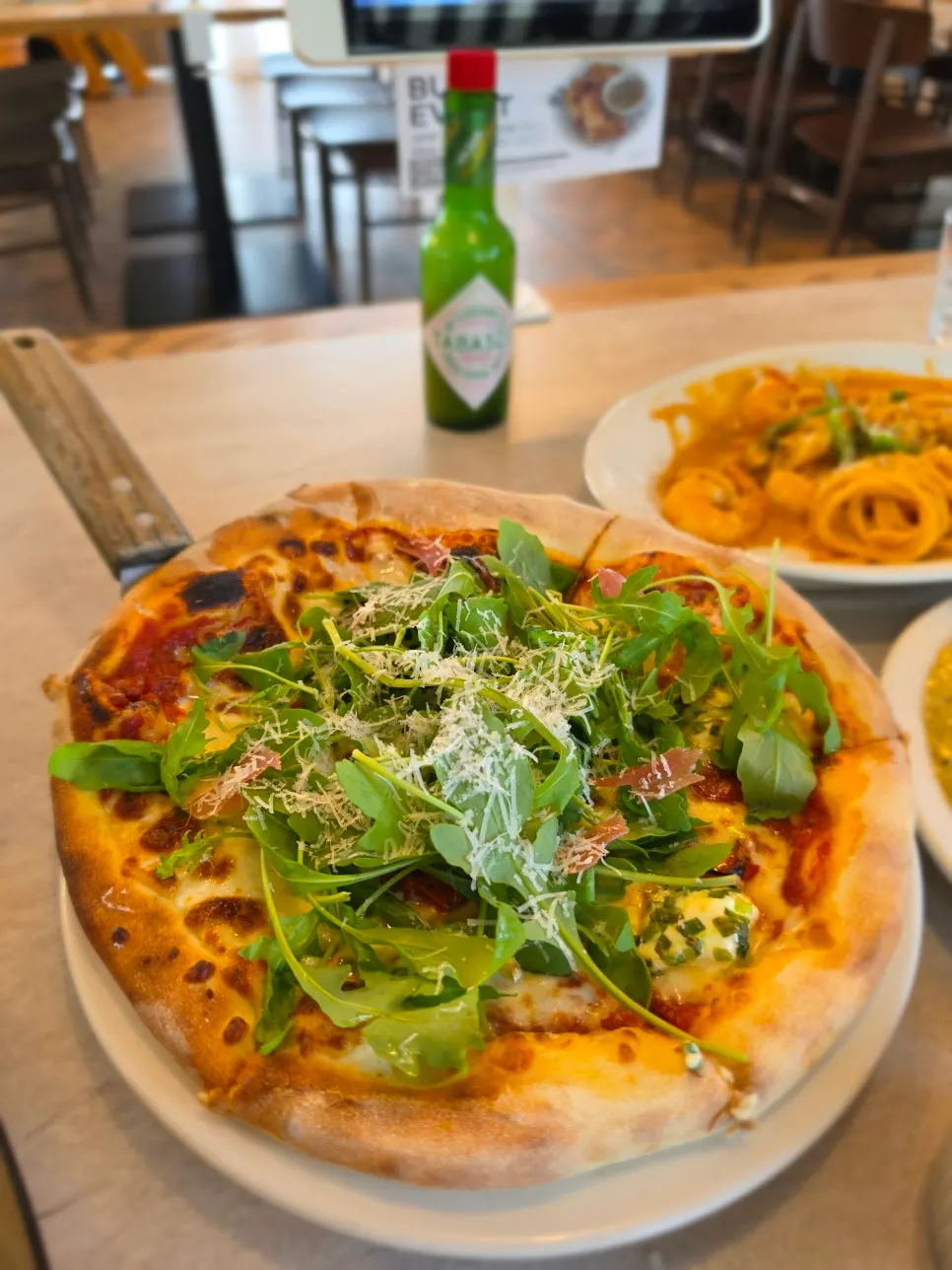 Prosciutto pizza piled high with rocket (arugula)
