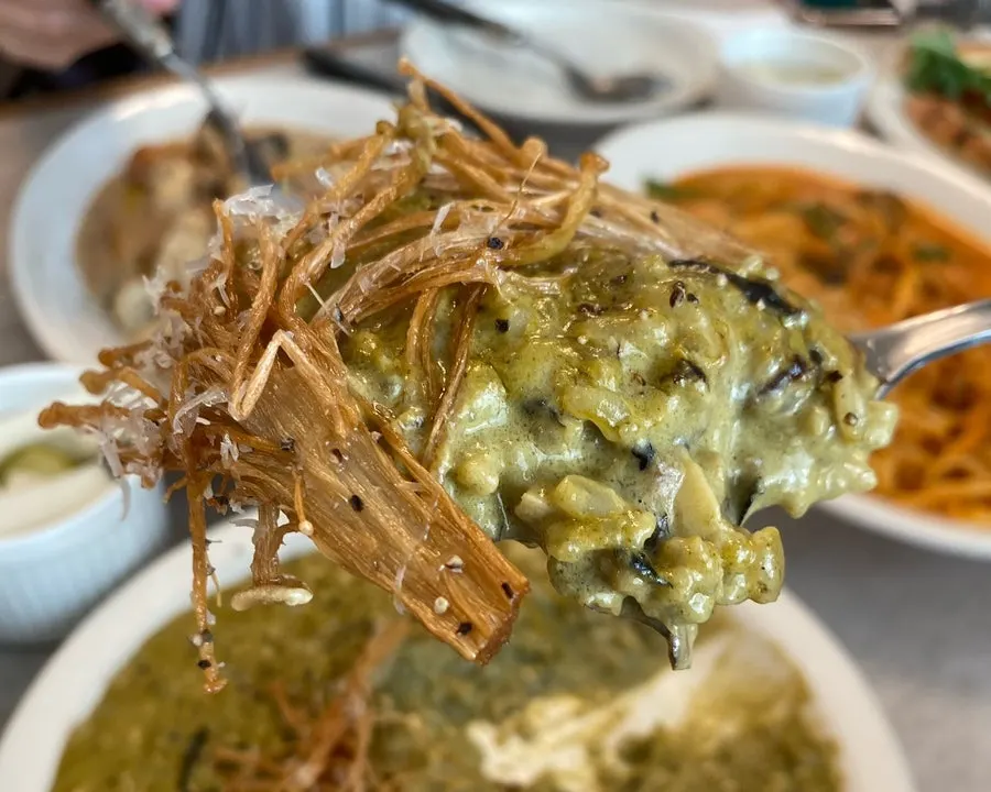 A spoonful of abalone risotto topped with enoki mushrooms