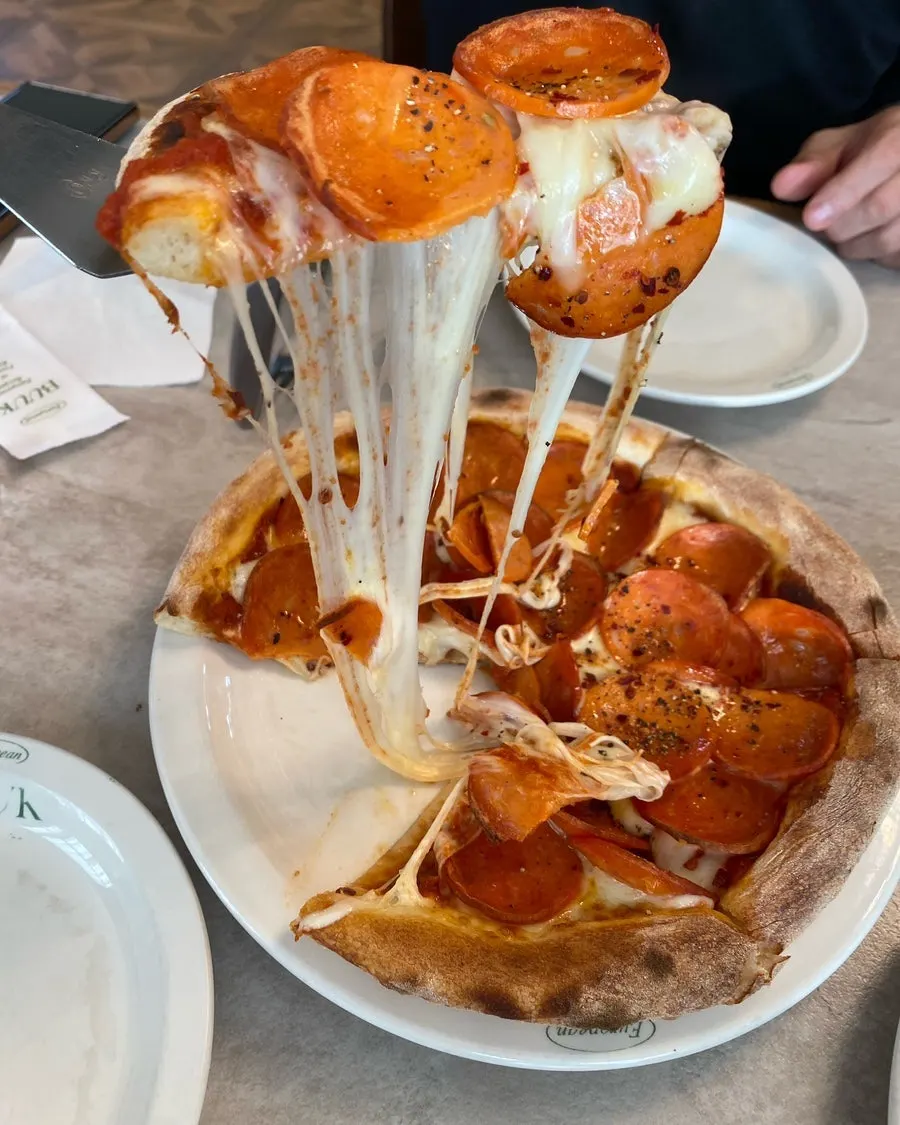 A slice of pepperoni pizza with stretchy cheese