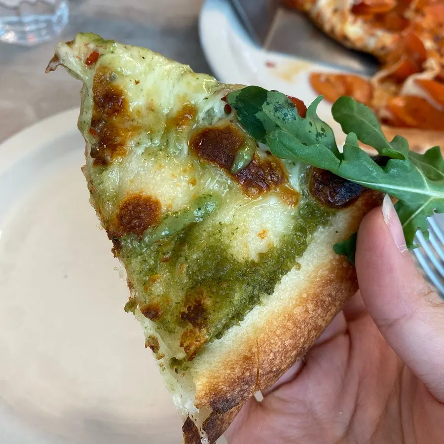 A slice of basil pesto pizza with fresh basil aroma