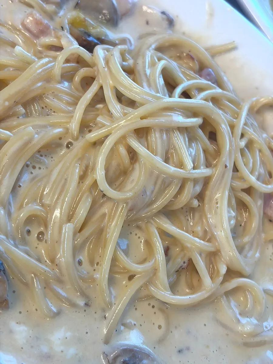 Thick carbonara cream pasta mixed with poached egg