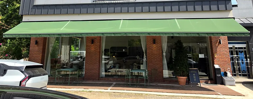 Exterior of Bueokgan Suwan Branch with floor-to-ceiling windows and green tarp