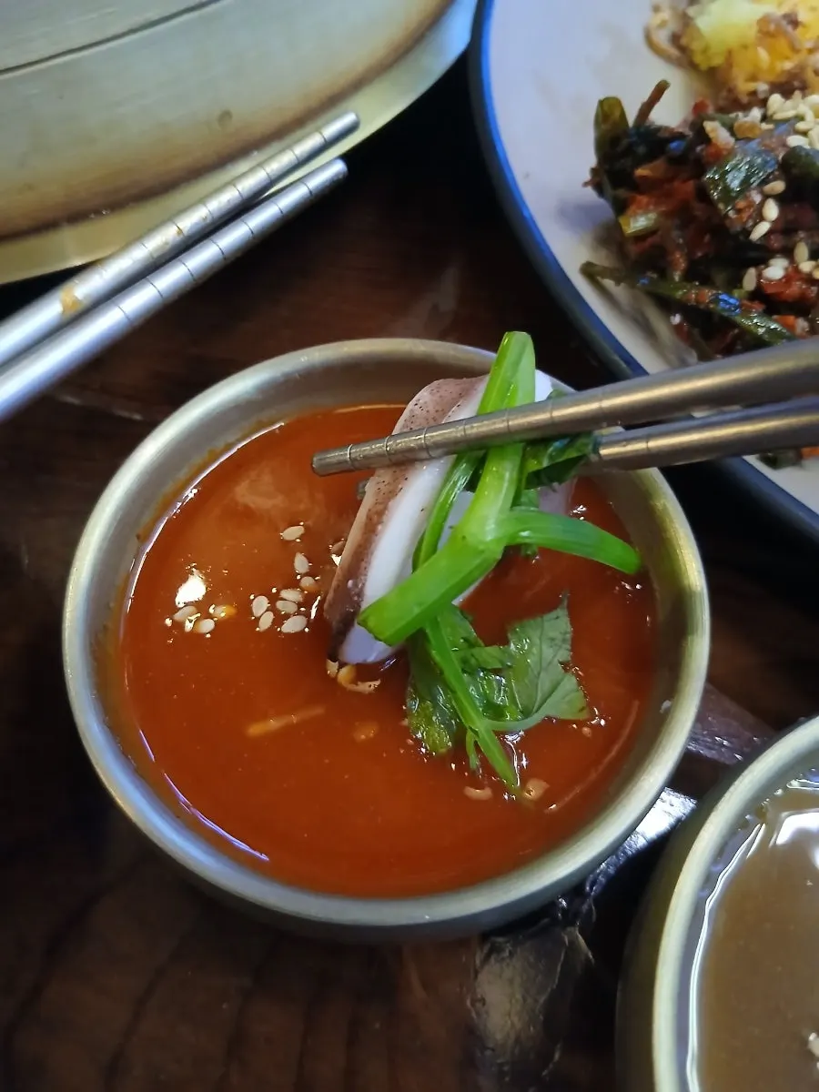 A piece of squid dipped in chojang with minari