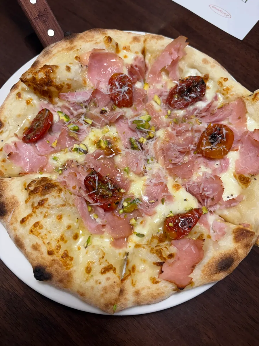 Slice of jambon pizza topped with sun-dried tomato