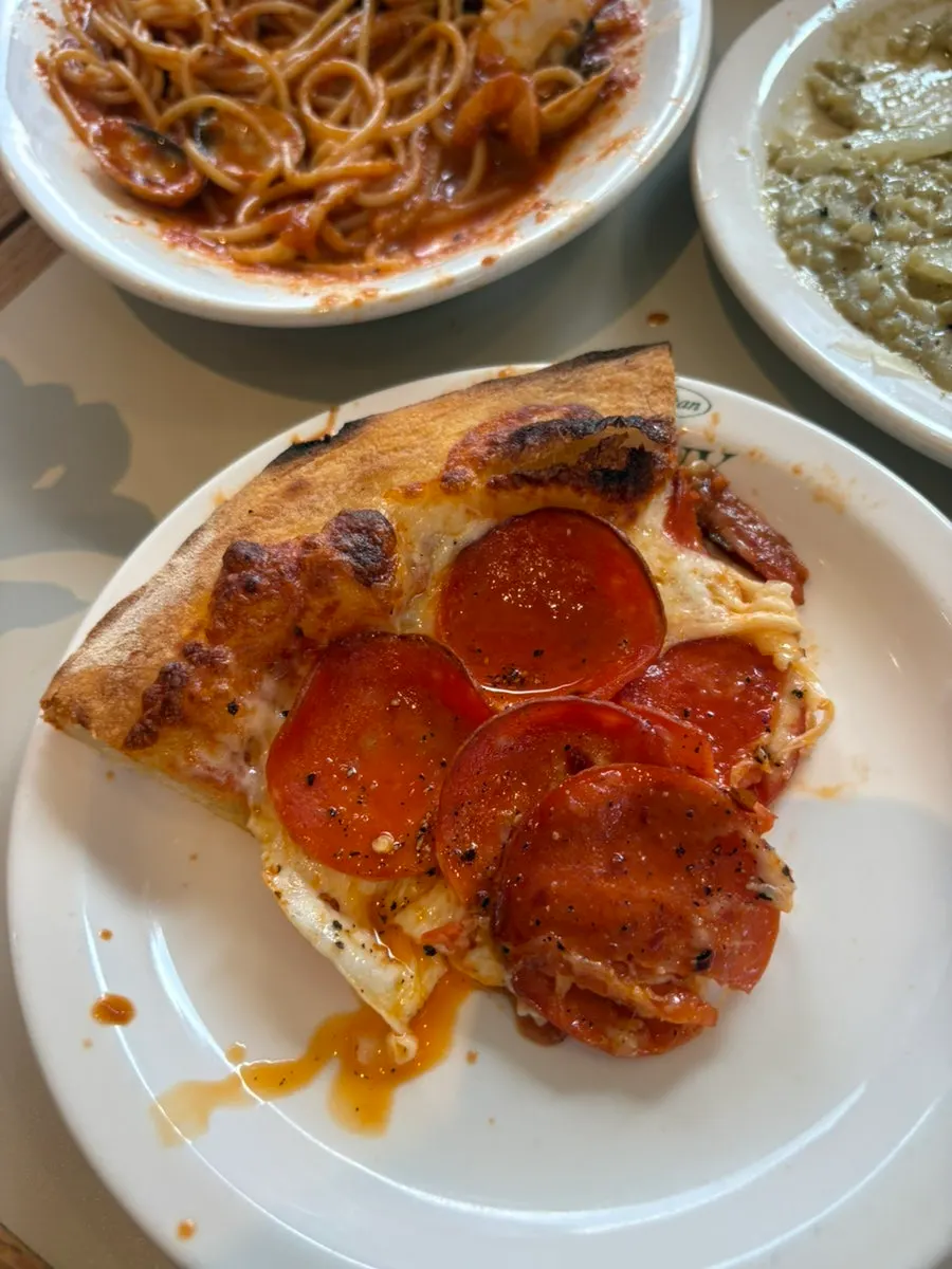 A slice of pepperoni pizza showing the light, thin dough