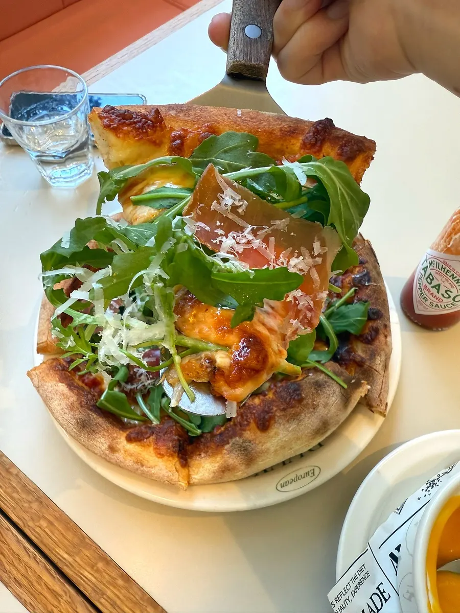 Jambon pizza piled high with arugula
