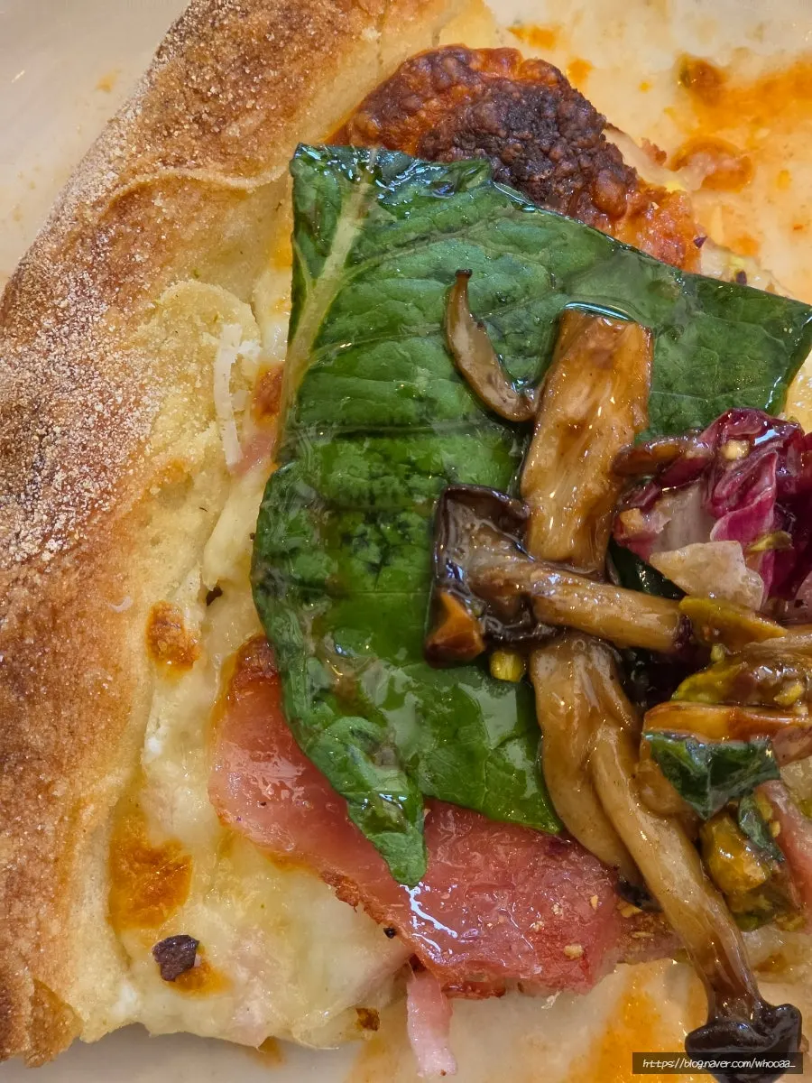 Hand holding a slice of pizza topped with salad