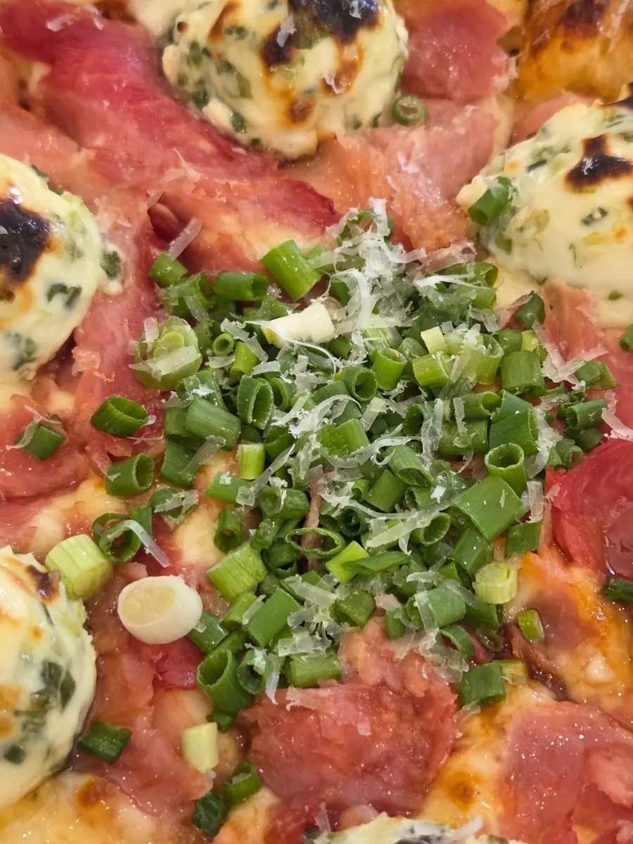 Surface of the pizza with generous cream cheese dollops