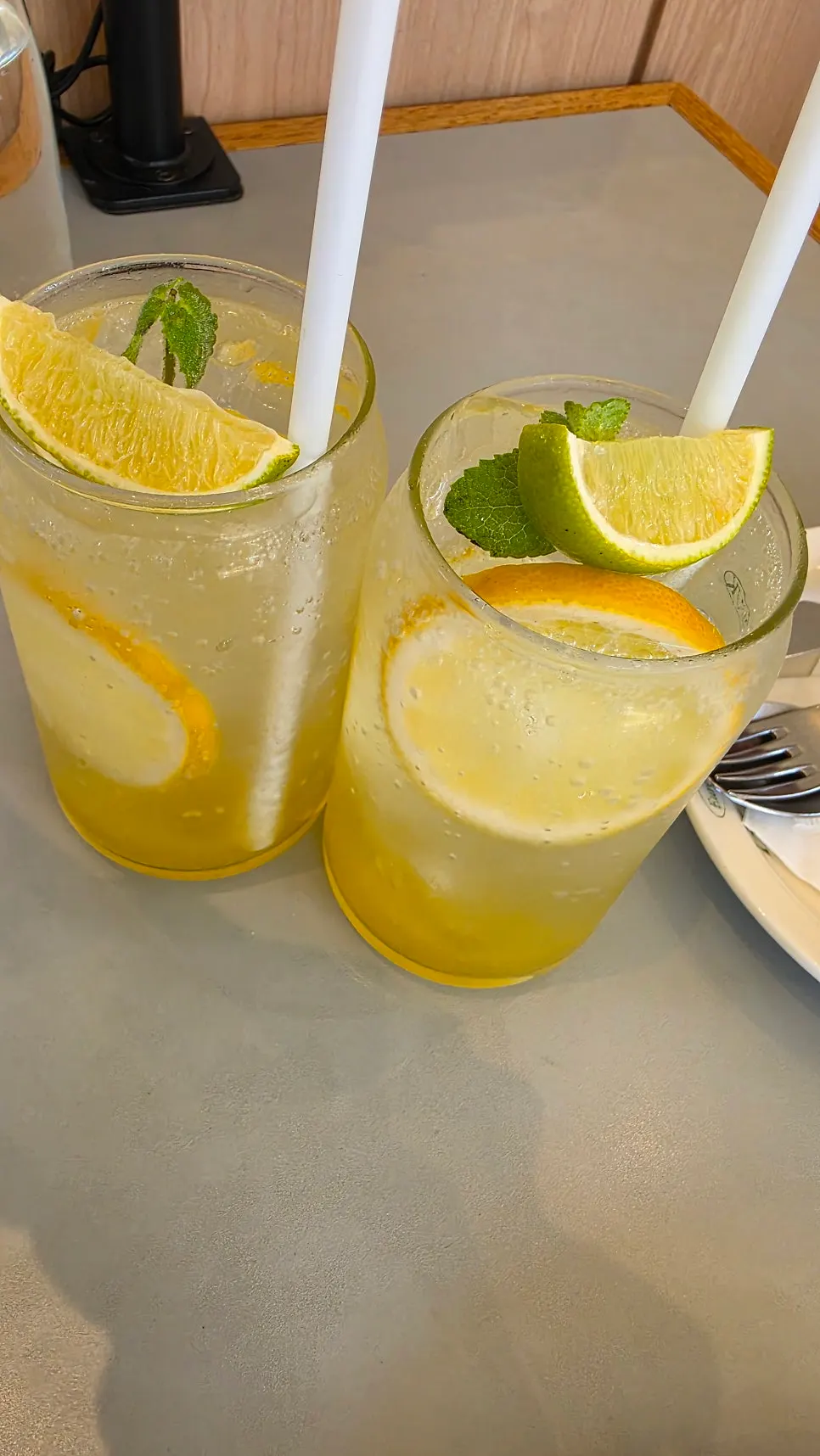 Two glasses of lemonade topped with lemon and mint