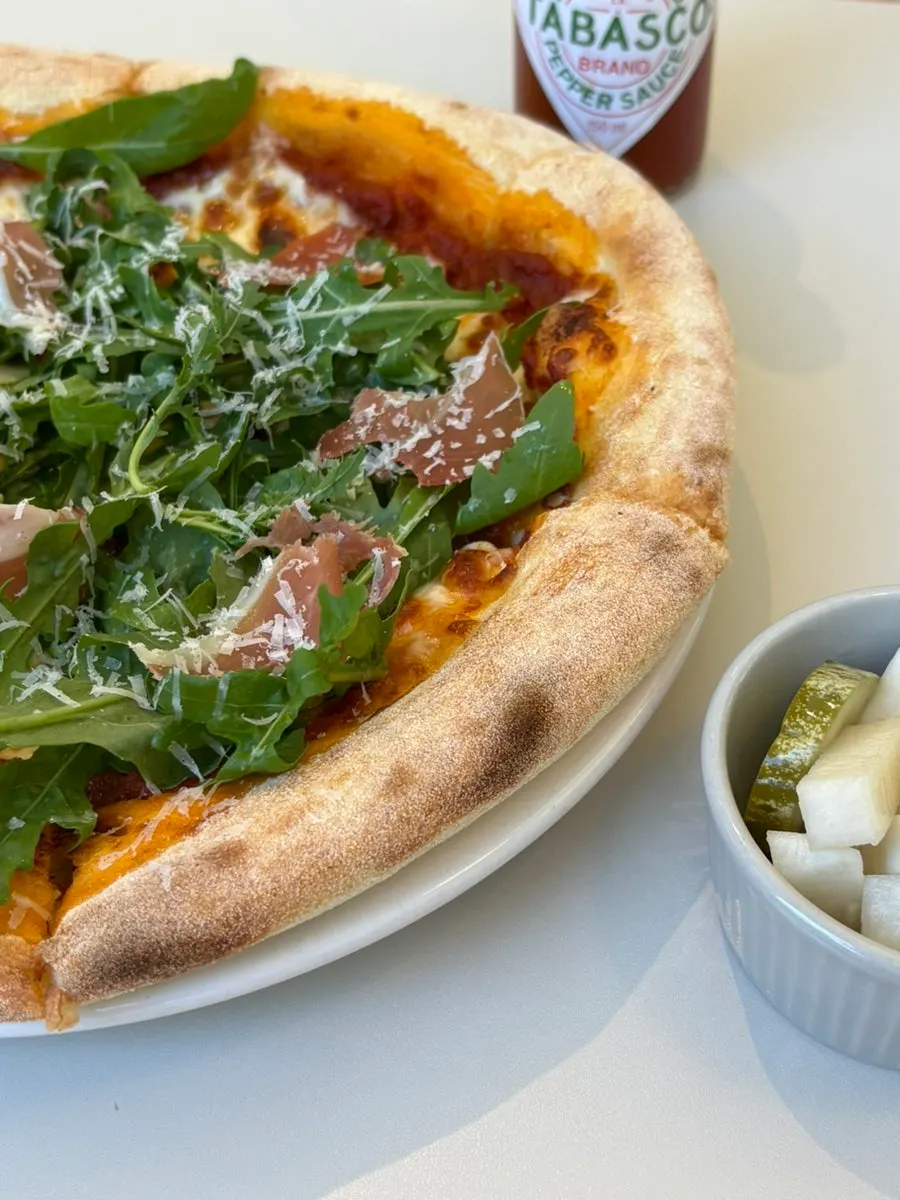 A slice of rucola pizza with stretching cheese