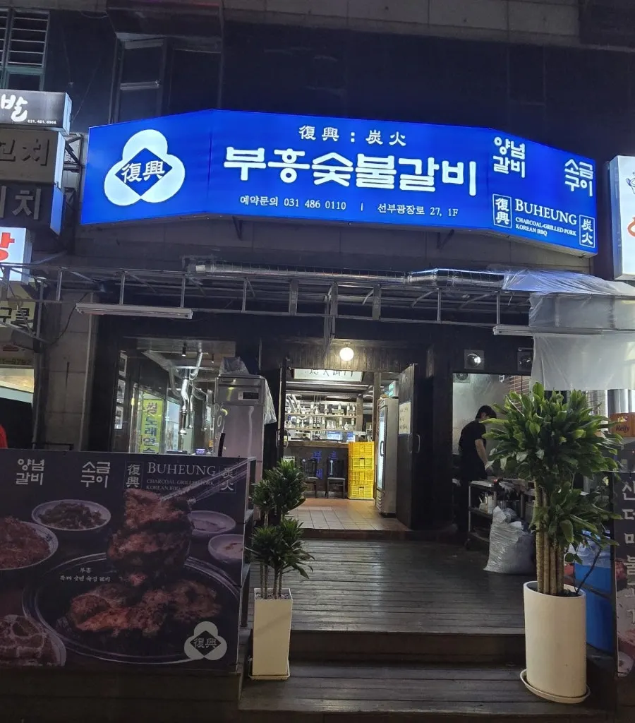 Blue signage and entrance of Buheung Charcoal Grilled Galbi on the Seonbugwangjang-ro main road