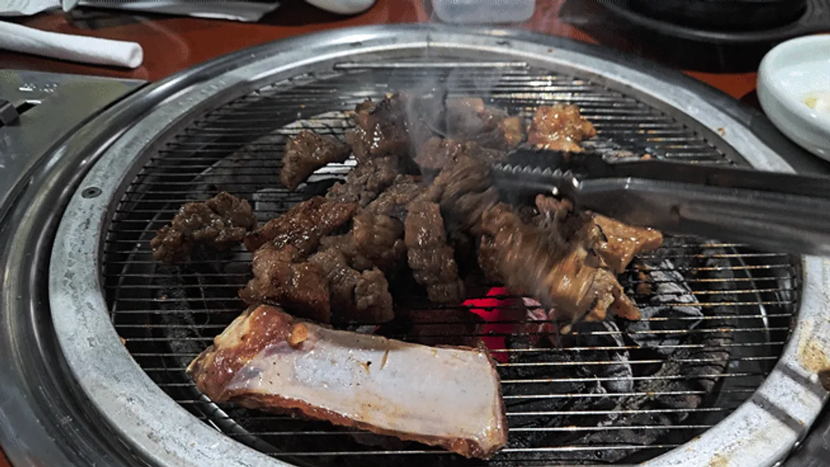 Seasoned pork galbi cooking on the charcoal grill grate