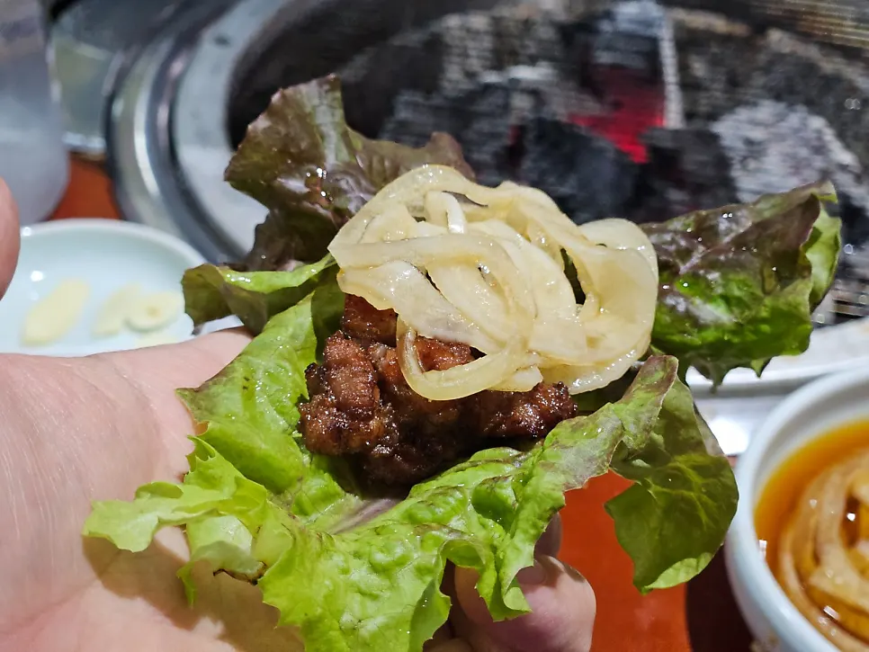 A piece of seasoned pork galbi eaten with pickled onions