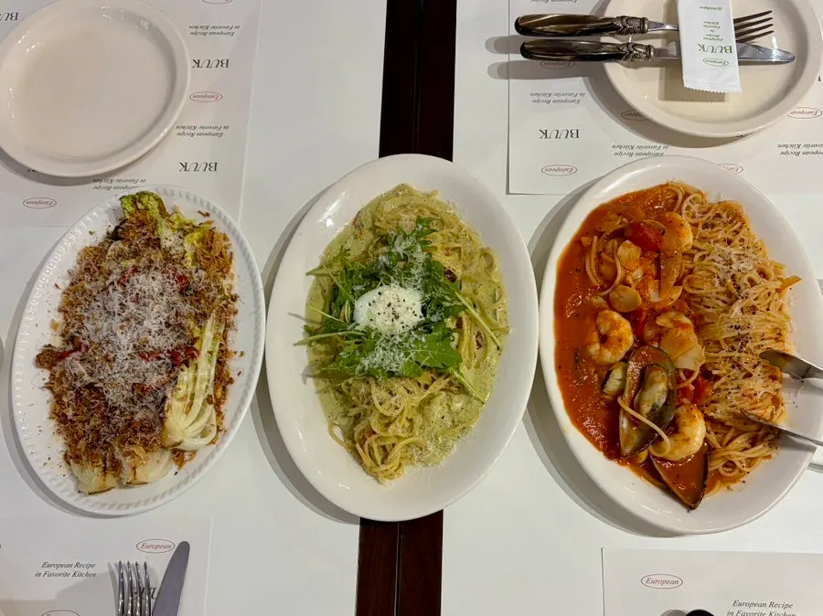 A spread of pasta, pizza and salad shared by four friends