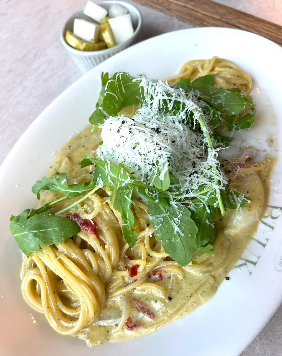 Basil pesto cream pasta topped with a poached egg