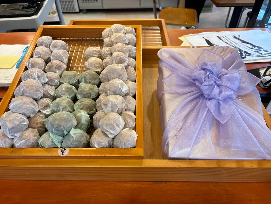 Wooden tray counter piled with paper-wrapped walnut pastries