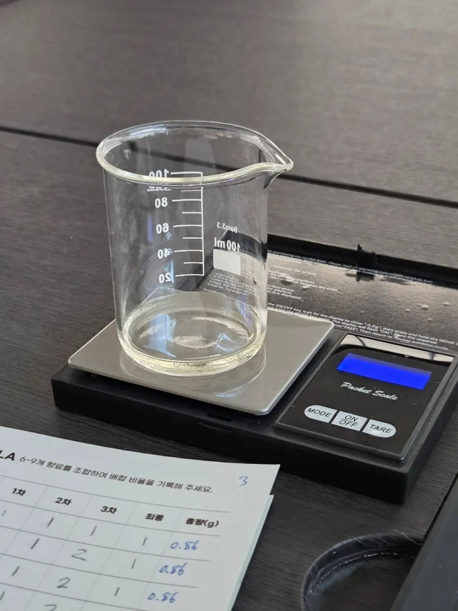 Measuring and blending fragrance oils in a beaker on a scale