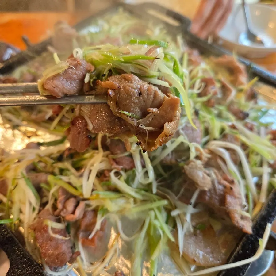 A bite of charcoal scallion pancake bulgogi picked up with chopsticks