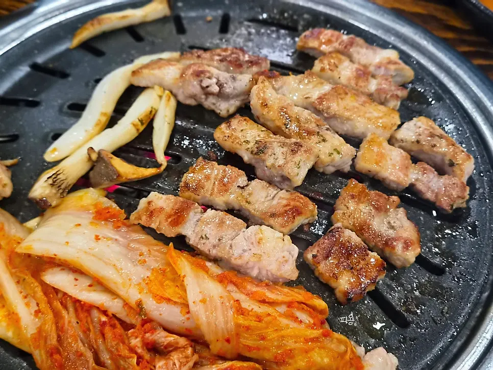 불판에 삼겹살과 버섯 김치 함께 굽는 모습