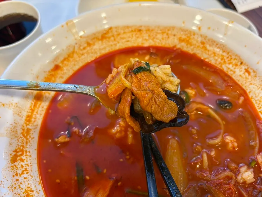 A spoonful of mixed rice topped with meat and cockles