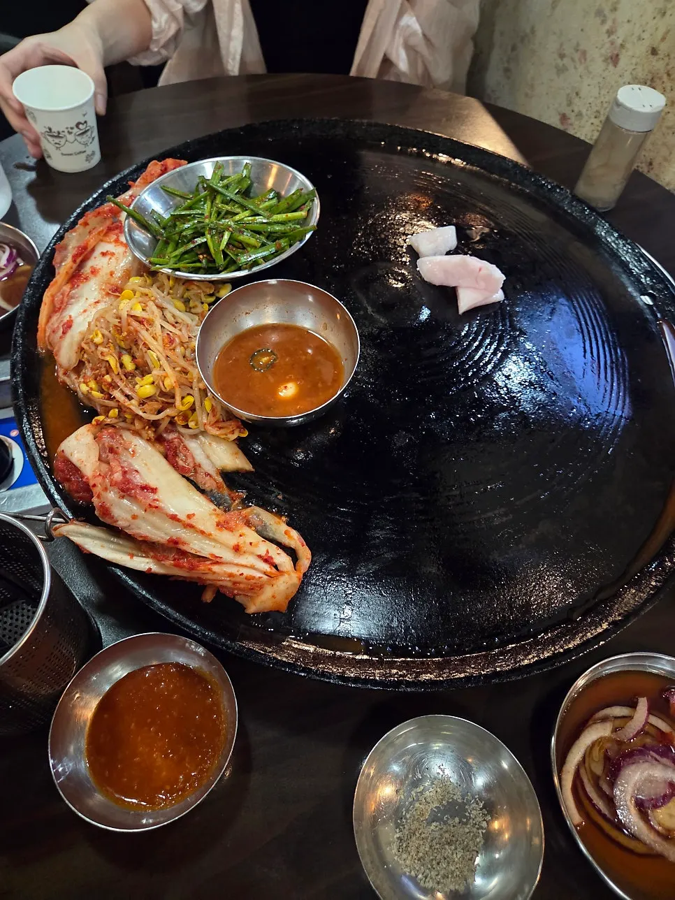 솥뚜껑 불판 가장자리에 깔린 포기김치와 콩나물무침