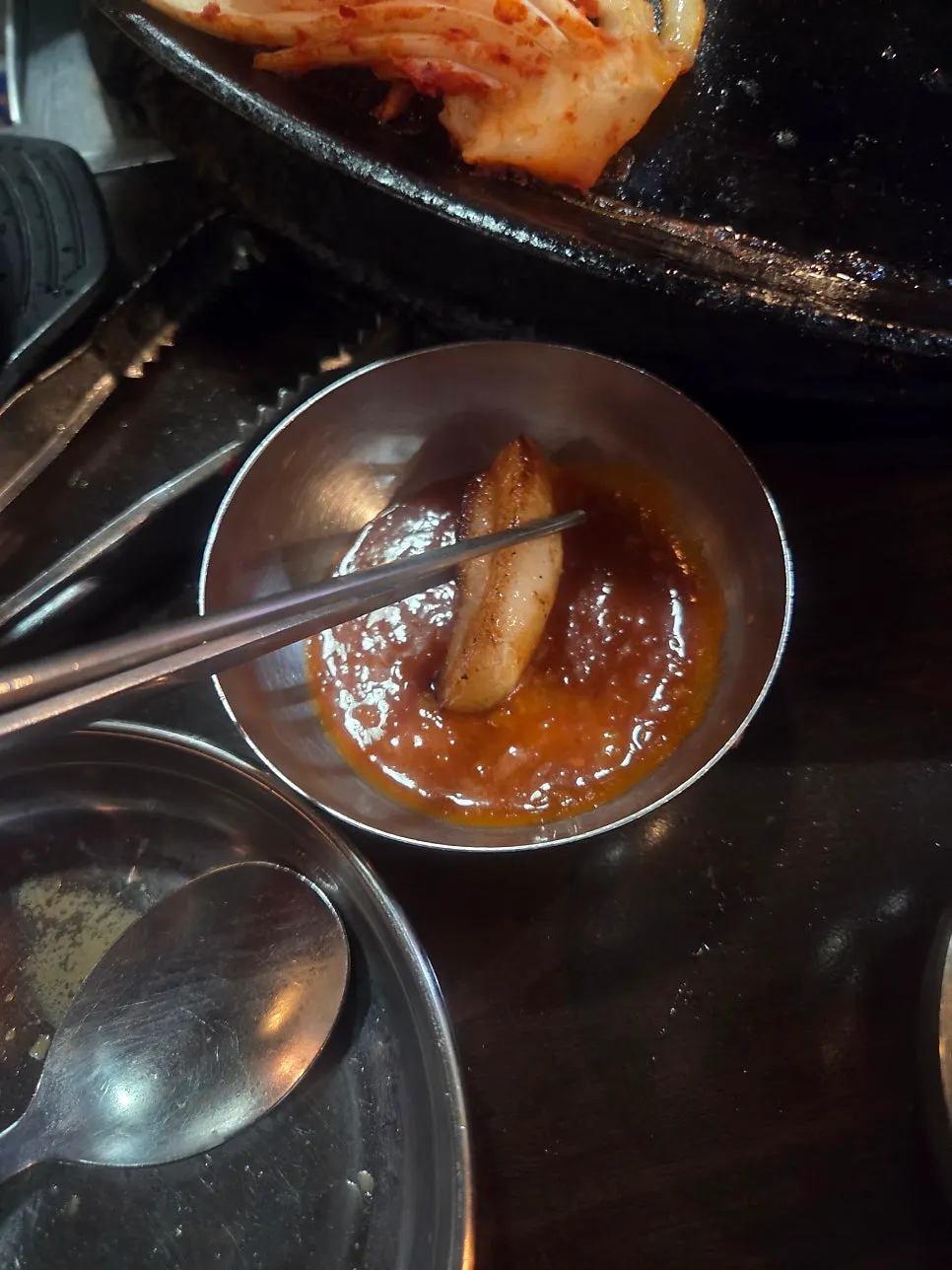 잘 익은 고기 한 점을 멜젓 소스에 찍는 모습