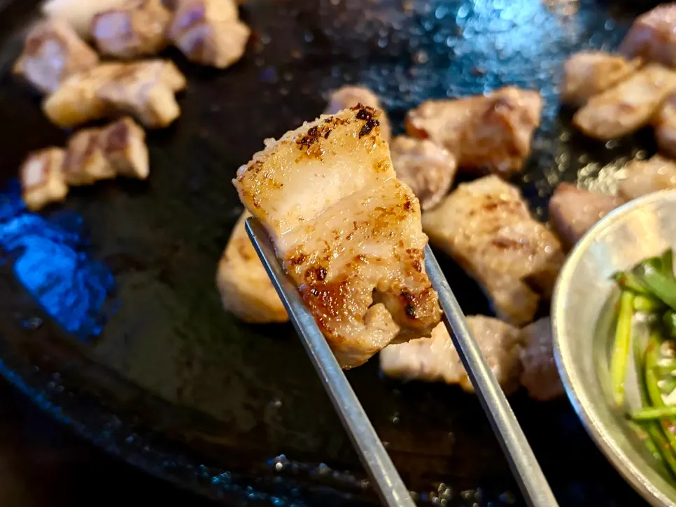 Staff grilling meat on a cauldron lid