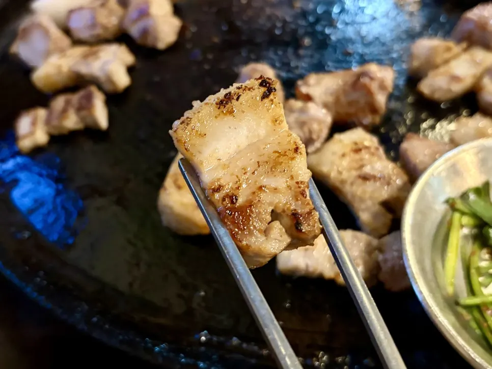 Staff grilling meat on a cauldron lid