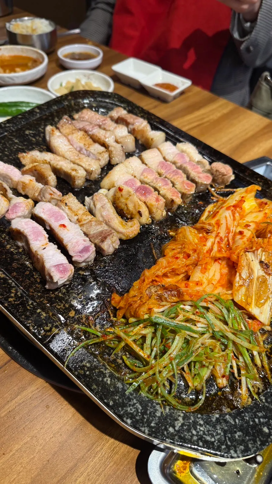 Kimchi and pork belly turning golden brown on the stone plate