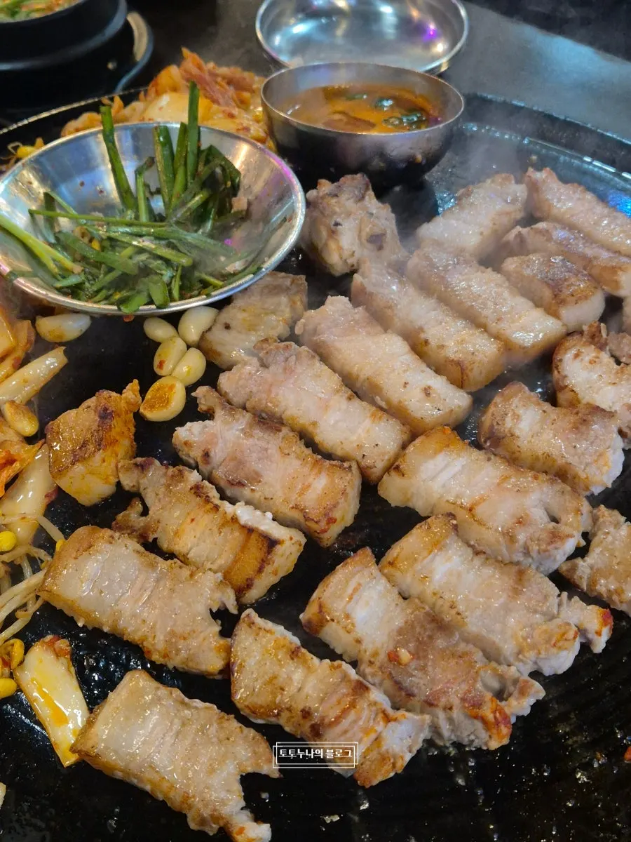 솥뚜껑 위에서 익어가는 삼겹살과 콩나물