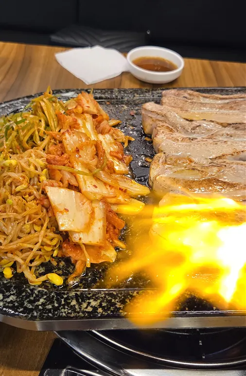 The owner searing the surface of the pork belly with a torch