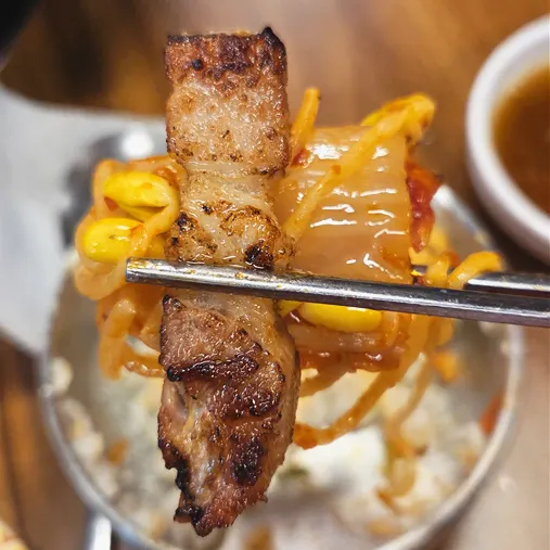 A lettuce wrap with pork belly and scallion strips