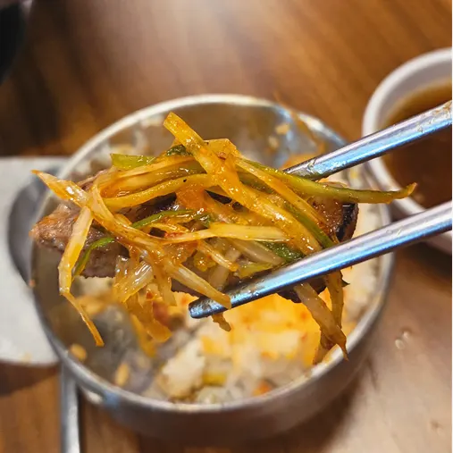 A piece of pork belly eaten with fresh kimchi