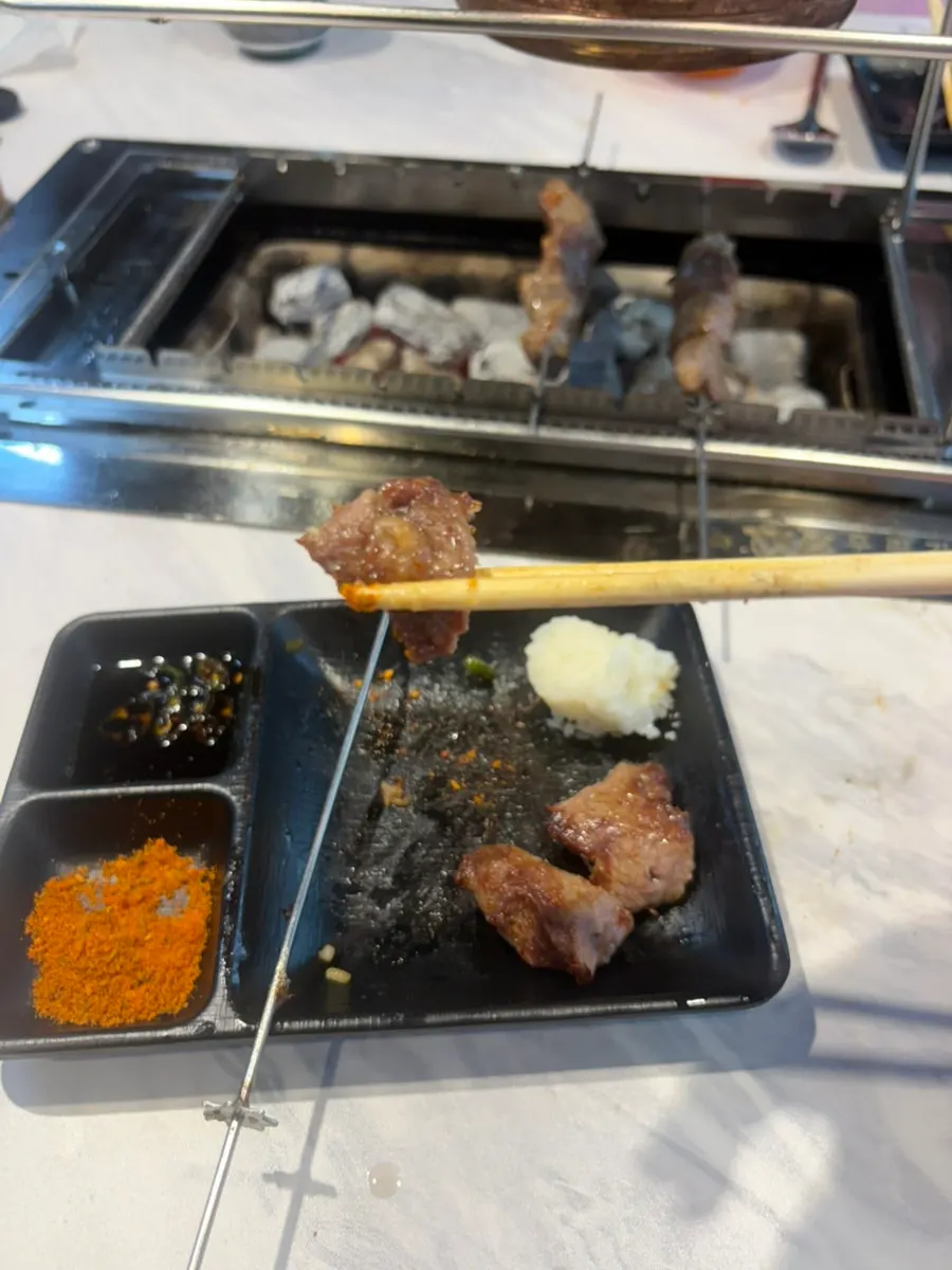 양꼬치를 한 점 집어 든 모습