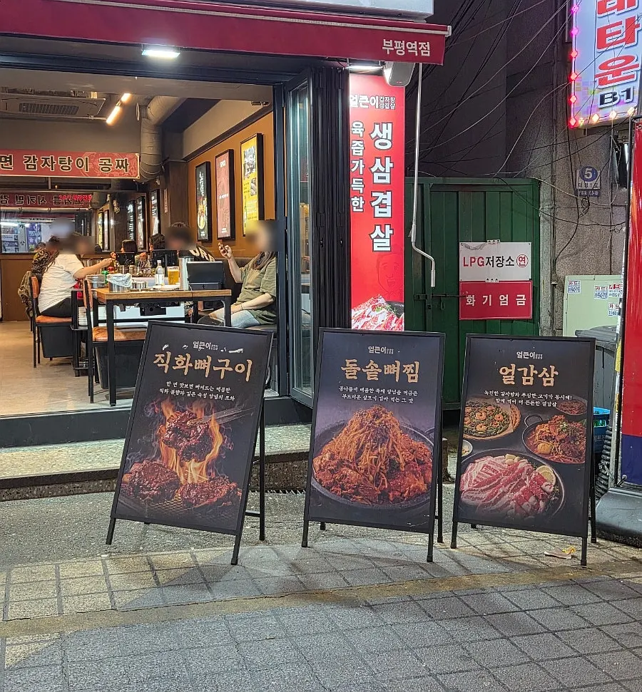 Sign board outside listing fire-grilled bone ribs, stone-pot bone stew and other menu items