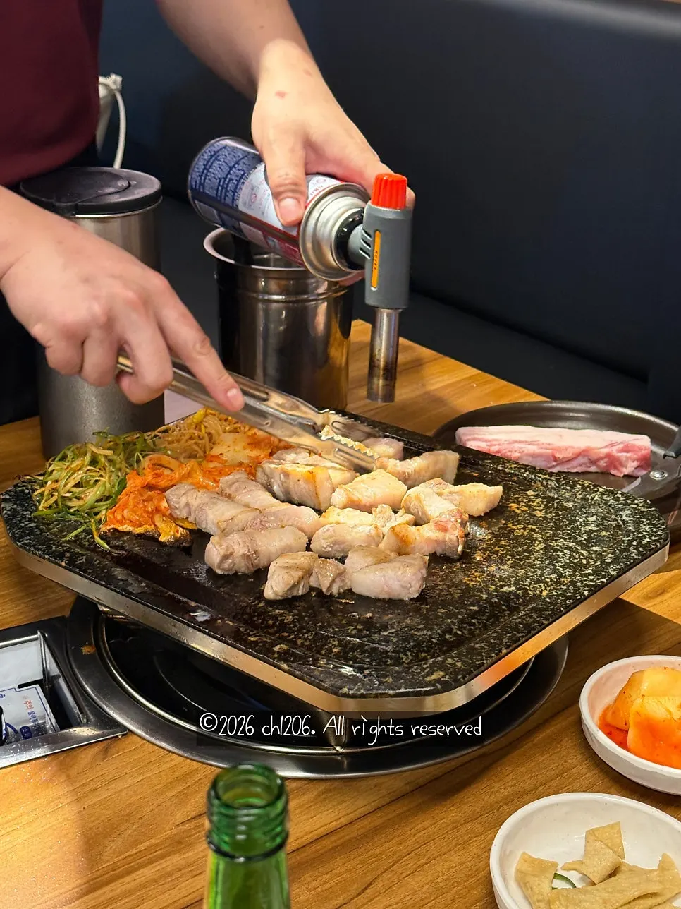 Pork belly grilling golden-brown alongside side dishes
