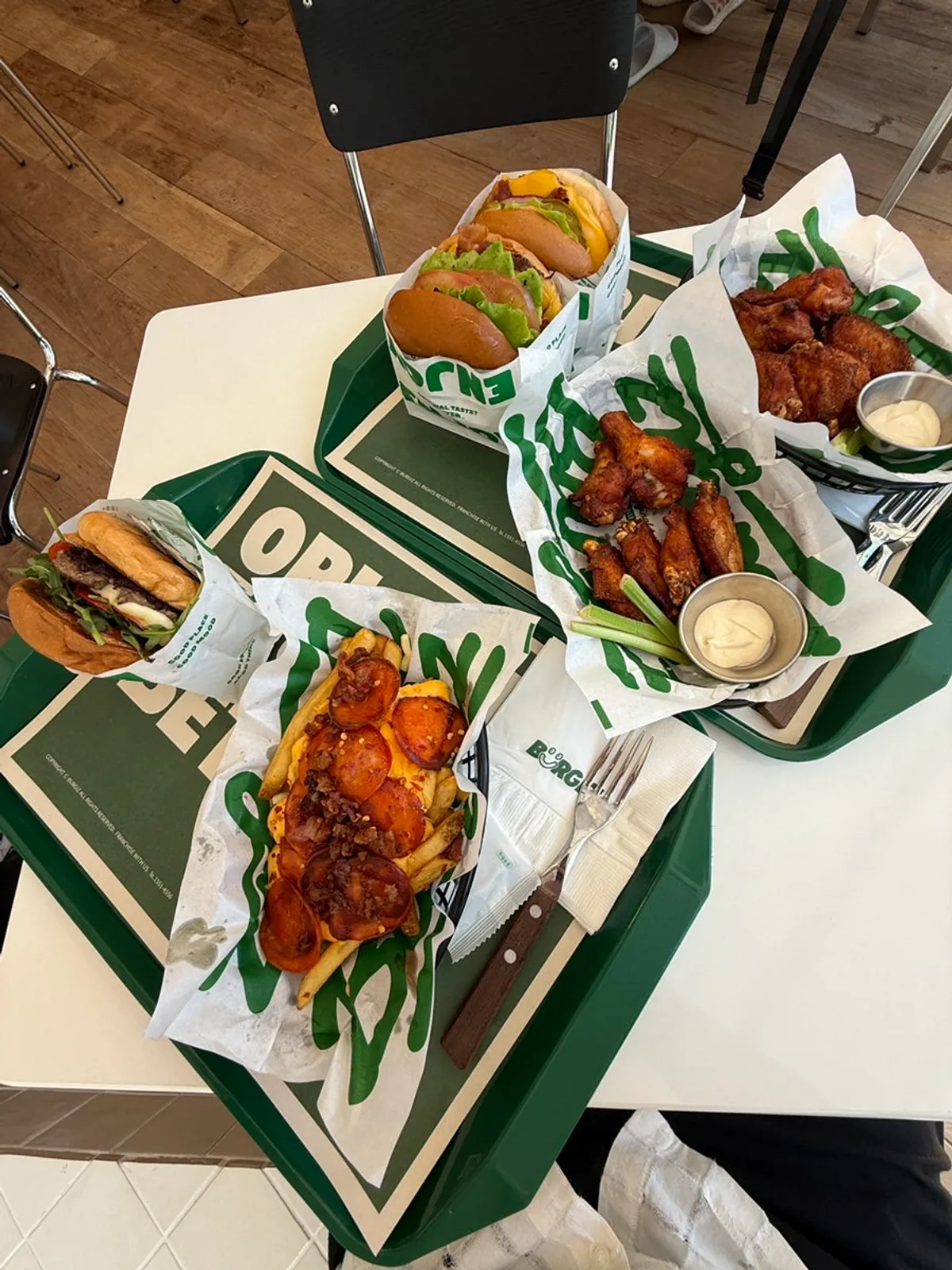 Three burgers and sides laid out on a green tray