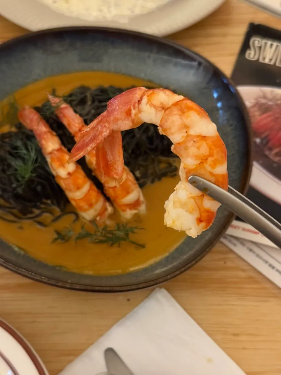 Fresh squid ink bisque pasta topped with red shrimp