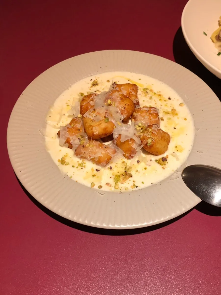 A plate of gnocchi bites topped with Comté cheese sauce