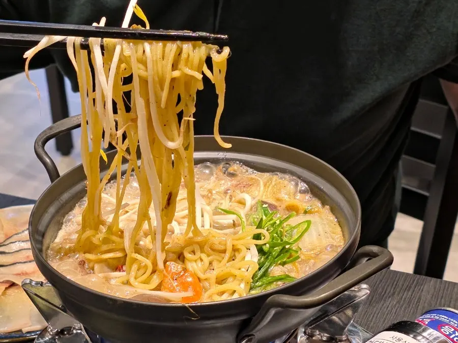 A pot of spicy soup full of bean sprouts
