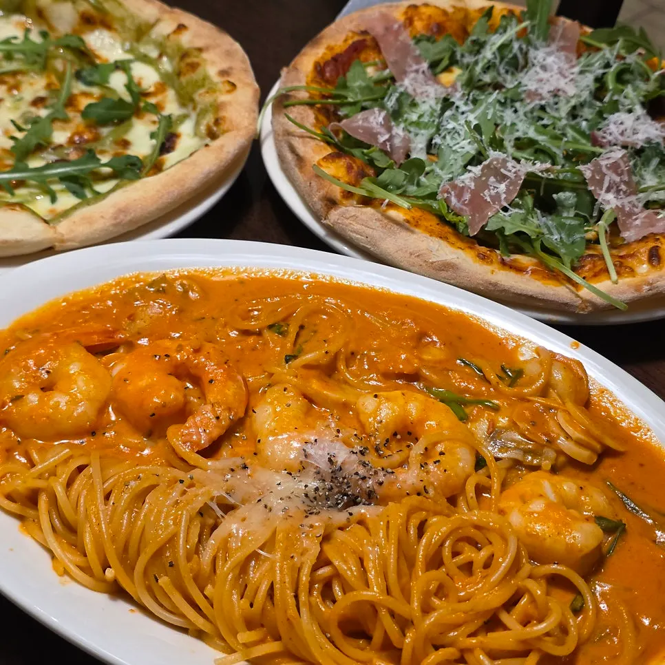 Rosé pasta and two pizzas on the table