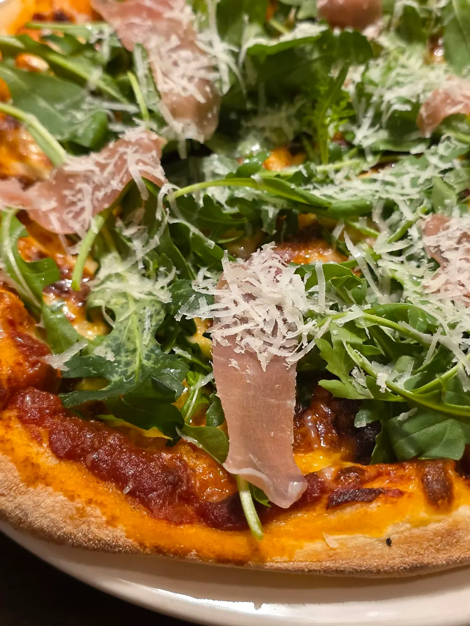 Pizza topped with arugula and prosciutto