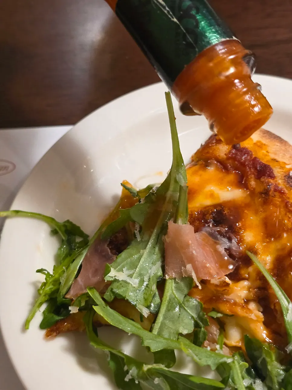 Arugula prosciutto pizza with hot sauce