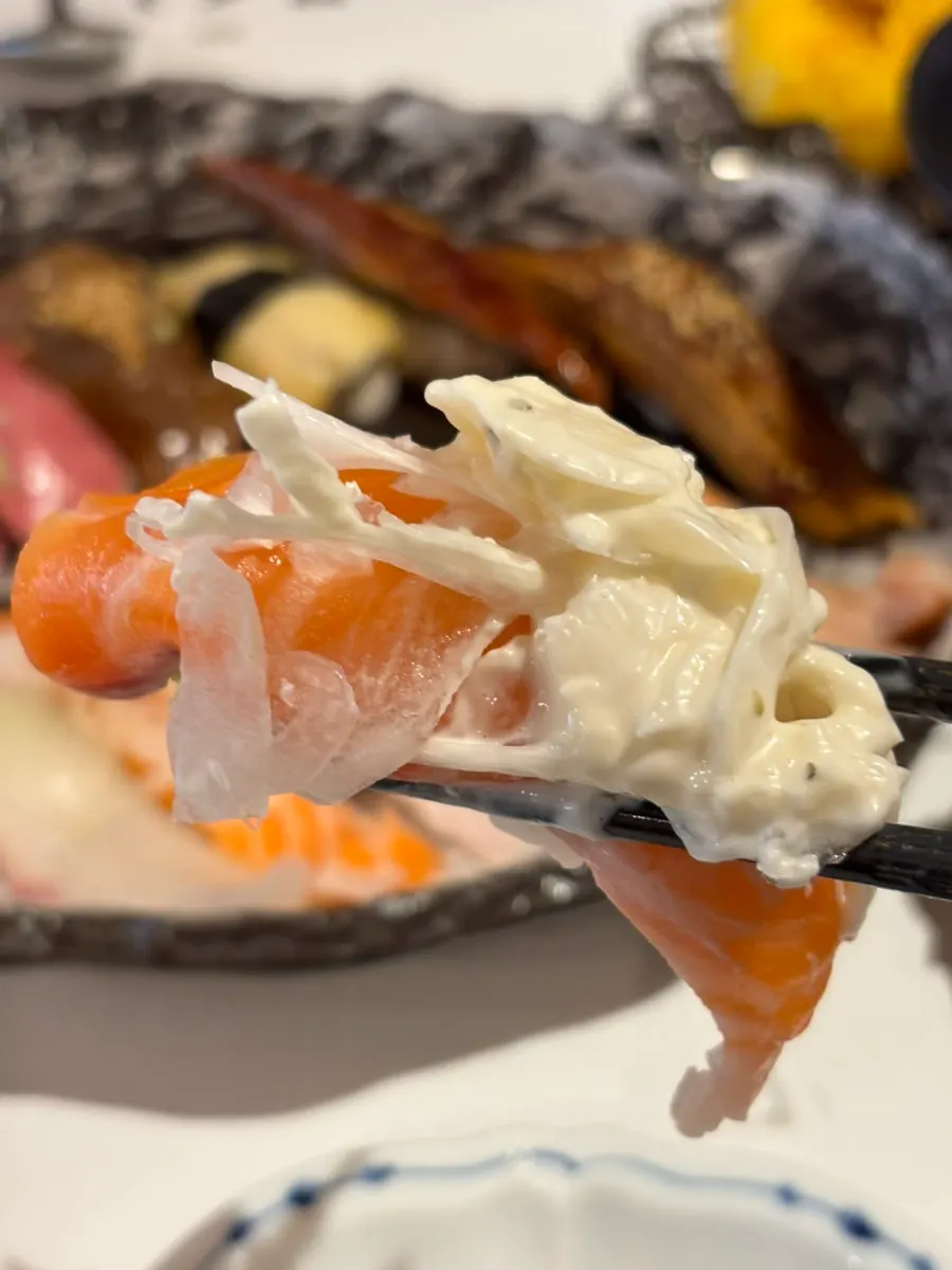 Piece of raw fish salmon sushi draping past the rice