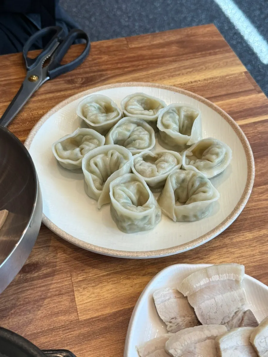 A bite of dumpling and bibim milmyeon on a spoon