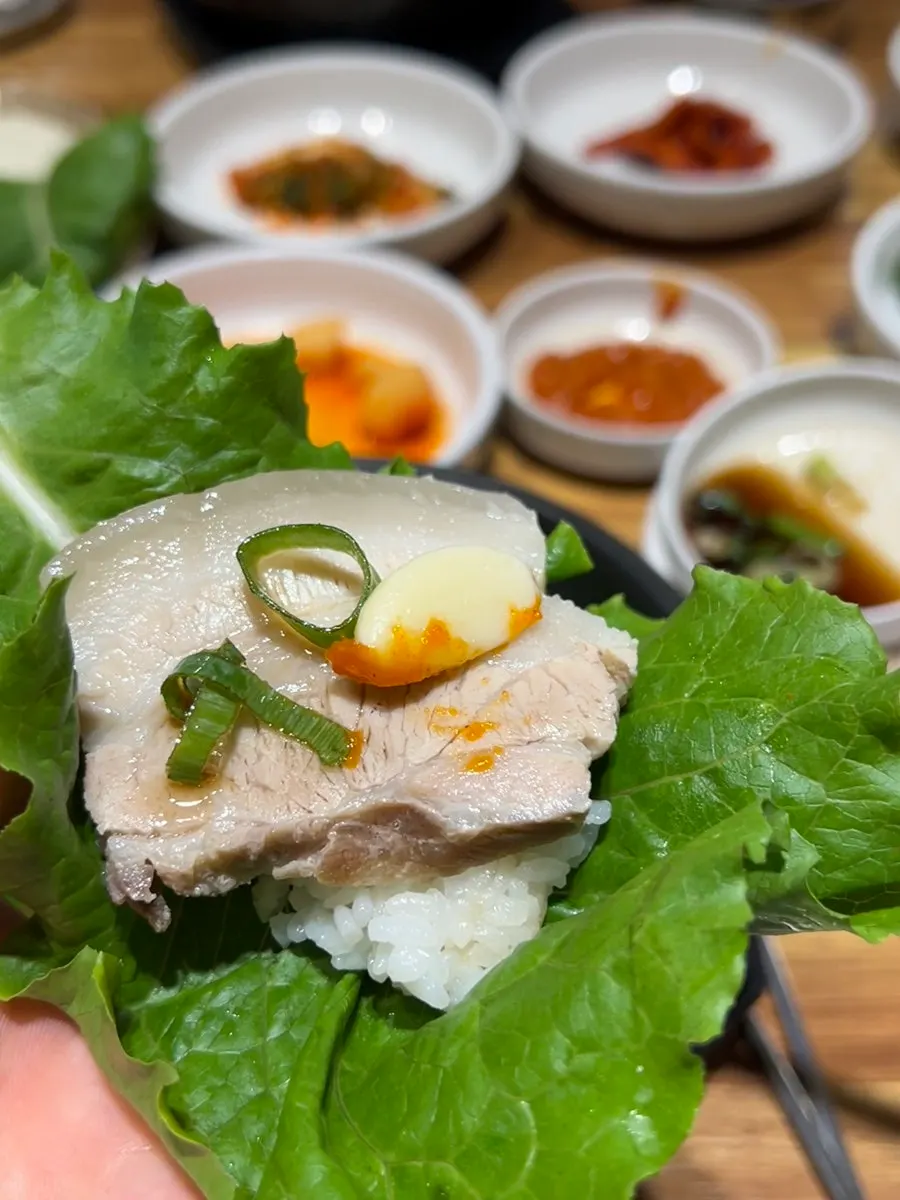 A piece of suyuk topped with salted shrimp and dried radish strips