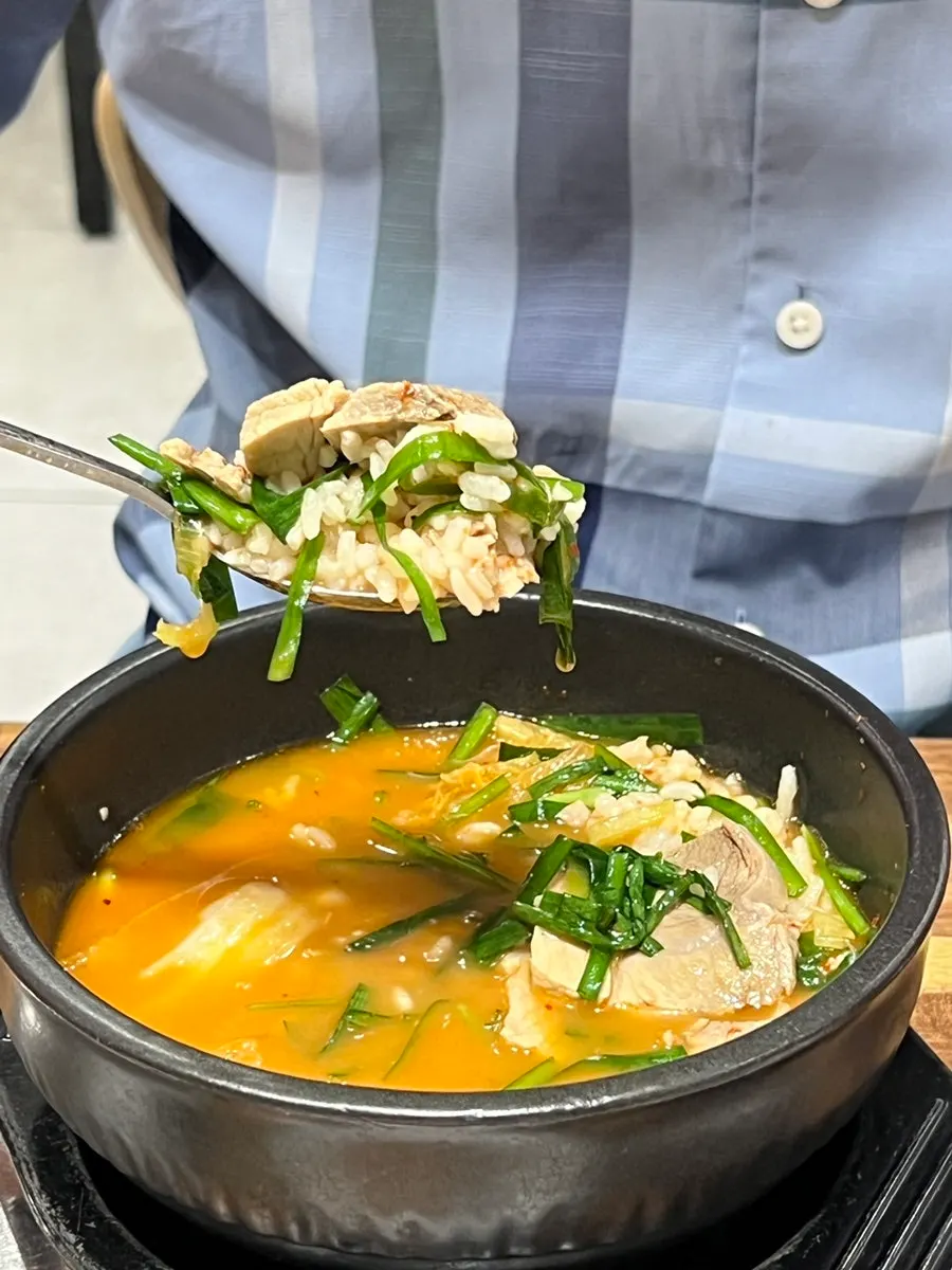 Dwaeji gukbap with kimchi, chives and chili paste added